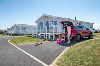 A family unpacking their car outside their holiday lodge in Northumberland