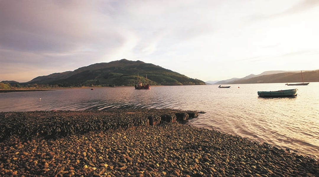 Boats on a loch in Scotland surrounded by mountains and hillside 