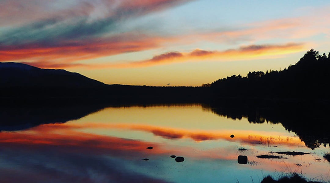 Sunset over a placid loch in Scotland