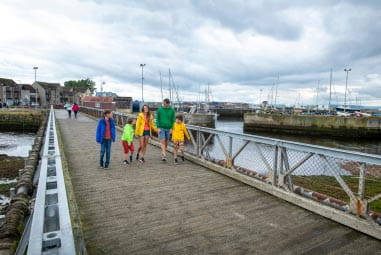People walking across a bridge in Nairn