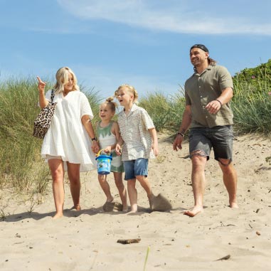 Family walking along the beach in the sun