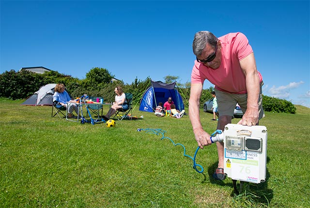 A man connecting to electricity point at Southerness Campsite