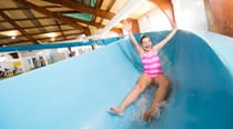 A girl sliding down a flume in an indoor swimming pool
