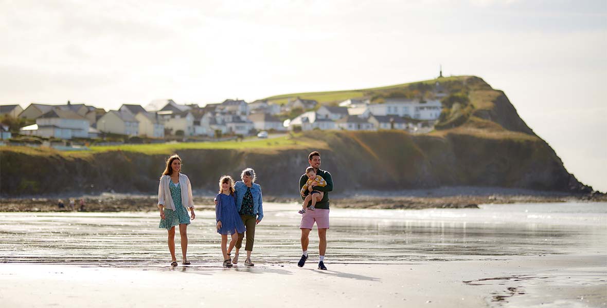 A family on holiday in Wales strolling along the beach