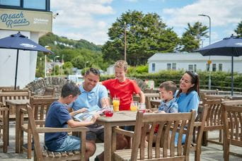 A family sitting in a beer garden at a Parkdean Resorts holiday park in Wales