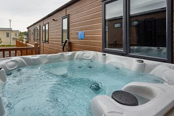 An empty hot tub next to a holiday lodge at a Parkdean Resorts holiday park