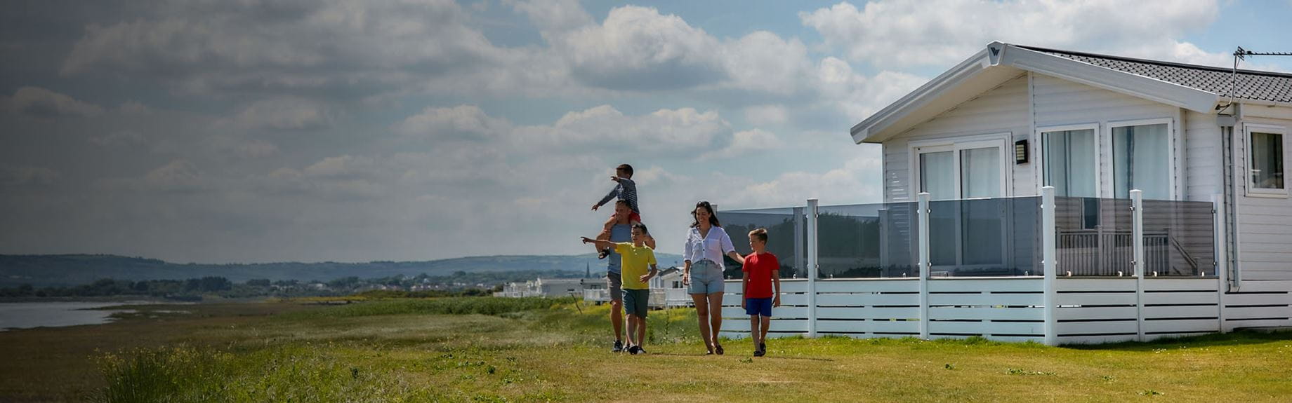 A family walking past a luxury holiday lodge at Carmarthen Bay Holiday Park in Wales