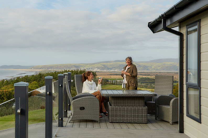 A mother and daughter on the veranda of their holiday lodge at Brynowen in Wales