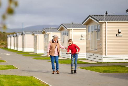 A grandmother and granddaughter walking past a row of caravans on a Parkdean holiday in Wales