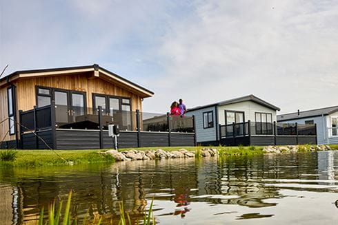 A couple admiring the view from the veranda on their lodge at Ty Mawr Holiday Park in North Wales