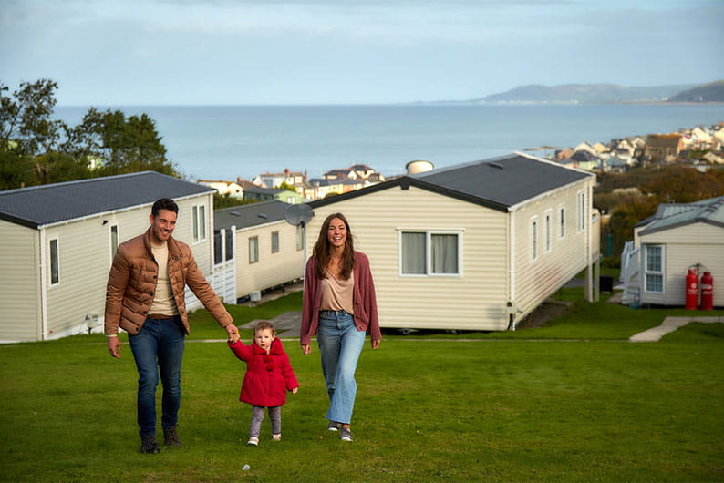 Parents holding hands with their child walking through Brynowen Holiday Park in Wales