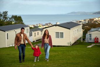 Parents holding hands with their child walking through Brynowen Holiday Park in Wales