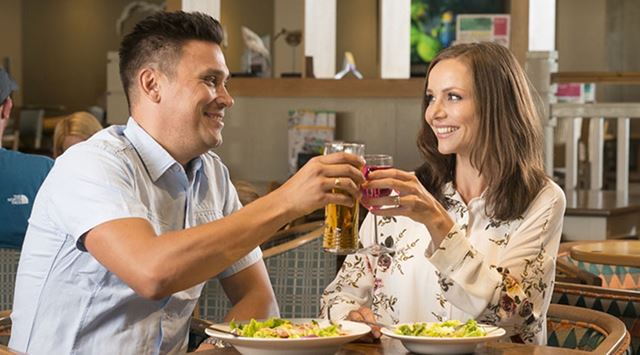 A couple toasting at dinner in the restaurant at a Parkdean Resorts campsite