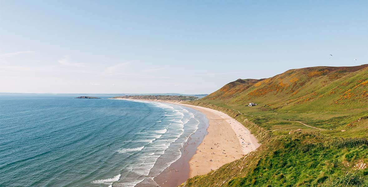 A wide sandy beach on a sunny day in Wales