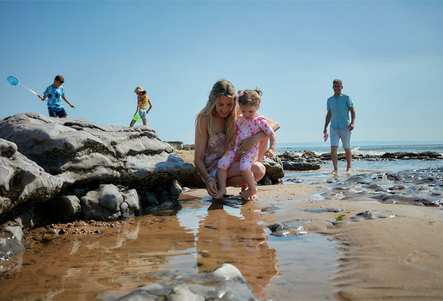 A mother and daughter exploring rockpools on a beach in Wales