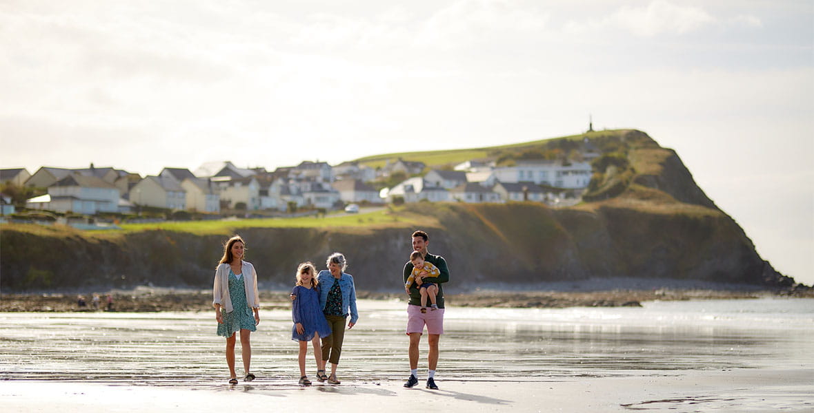 A family walking along the beach on a summer day in Wales