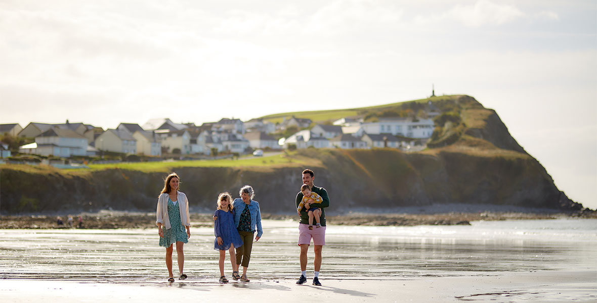 A family walking along the beach on a summer day in Wales