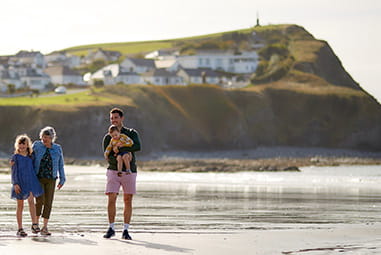A family walking along the beach on a summer day in Wales