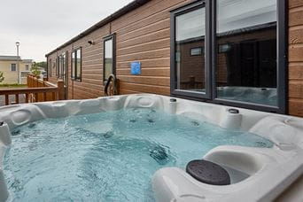 An empty hot tub next to a lodge at a Parkdean Resorts holiday park