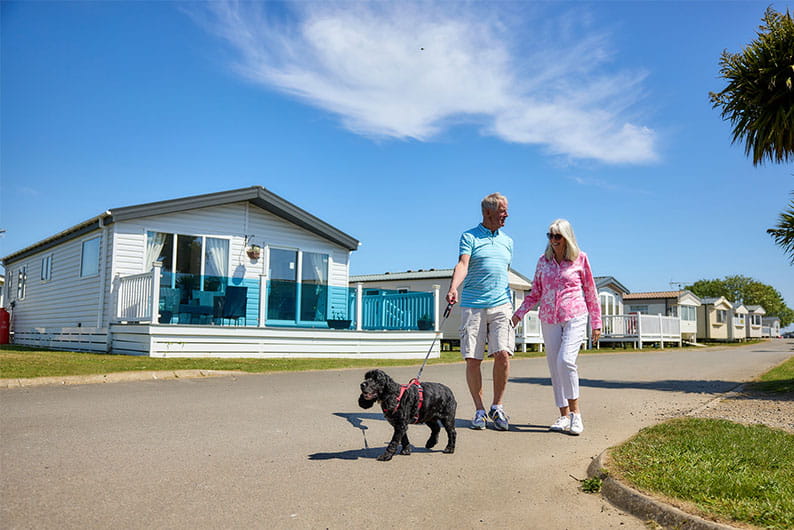 A couple walking their dog past their holiday lodge in Yorkshire