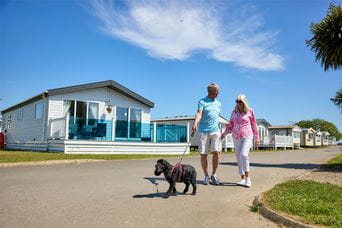 A couple walking their dog past their holiday lodge in Yorkshire