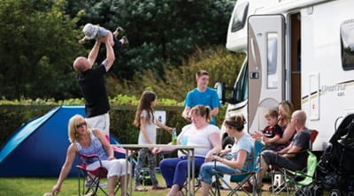 A large family sat enjoying the sun outside their touring caravan