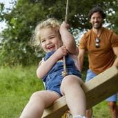 Man pushing child on swing