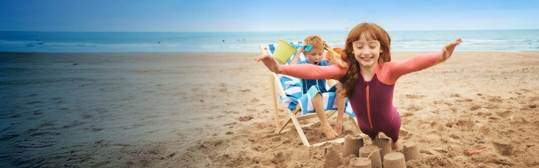 Little girl jumping over sandcastle