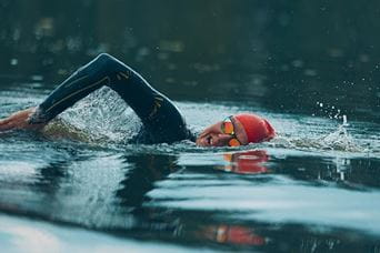Man wearing red swimming cap swimming in lake