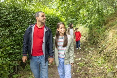 Dad and daughter walking through woods with mum walking behind with son