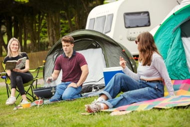 Friends sat on blanket outside tents