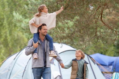 Dad with daughter on shoulders and holding sons hand