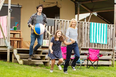 Family walking from glamping pod holding a beach ball