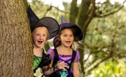 Two kids dressed as witches in woods