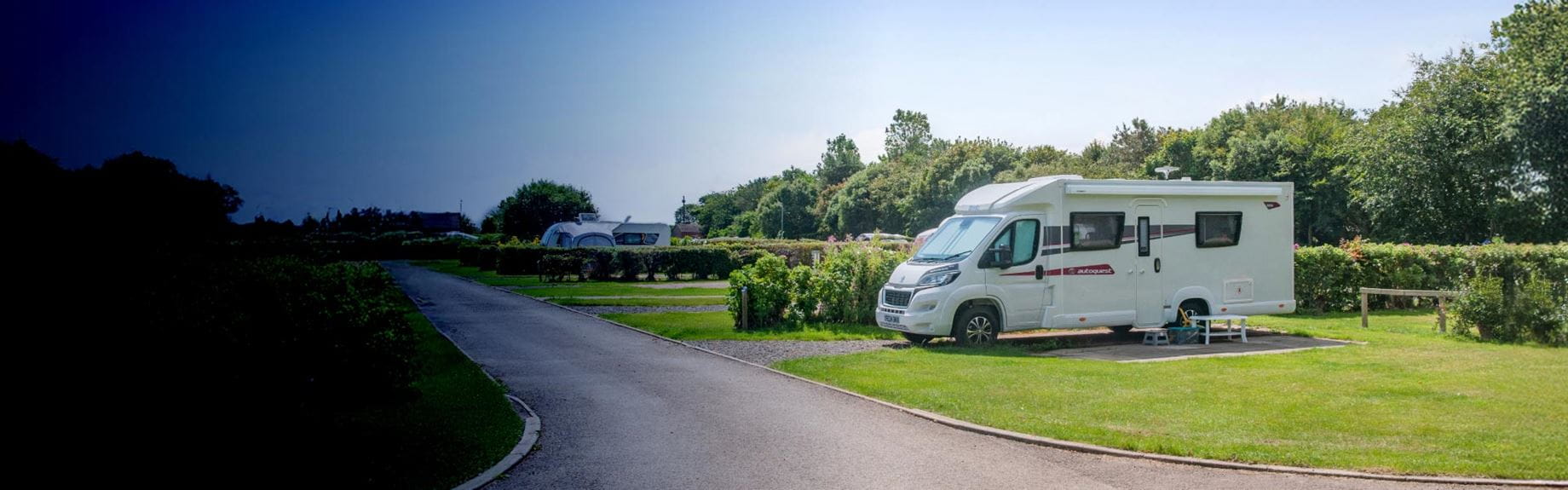 A motorhome on a grassy touring campsite pitch at Parkdean Resorts