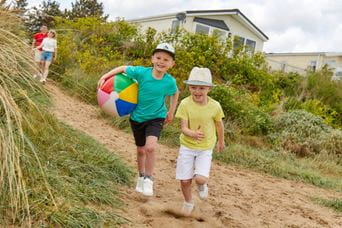 kids walking down sand dunes with a beach ball