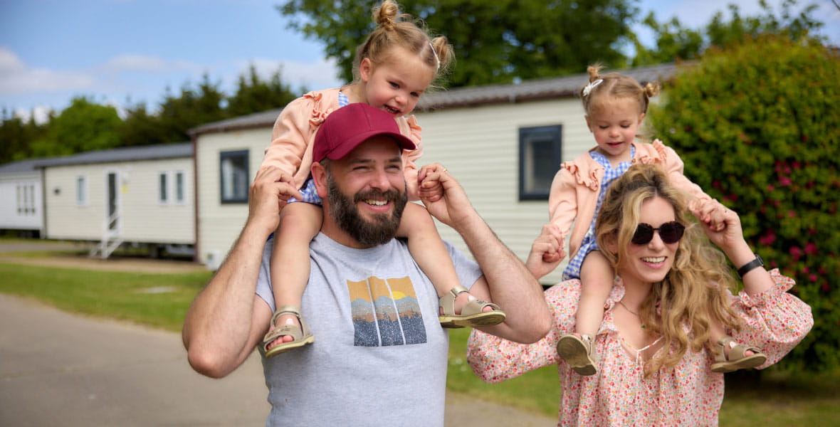 Family walking through parkdean resorts with children on shoulders