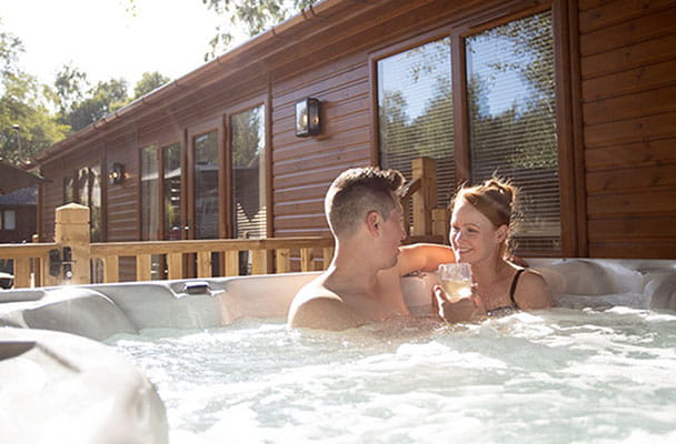 A couple relaxing in a hot tub outside their lodge