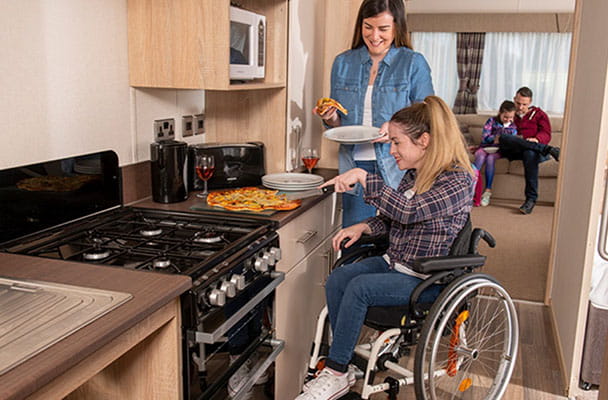 A woman in a wheelchair preparing a meal in her caravan