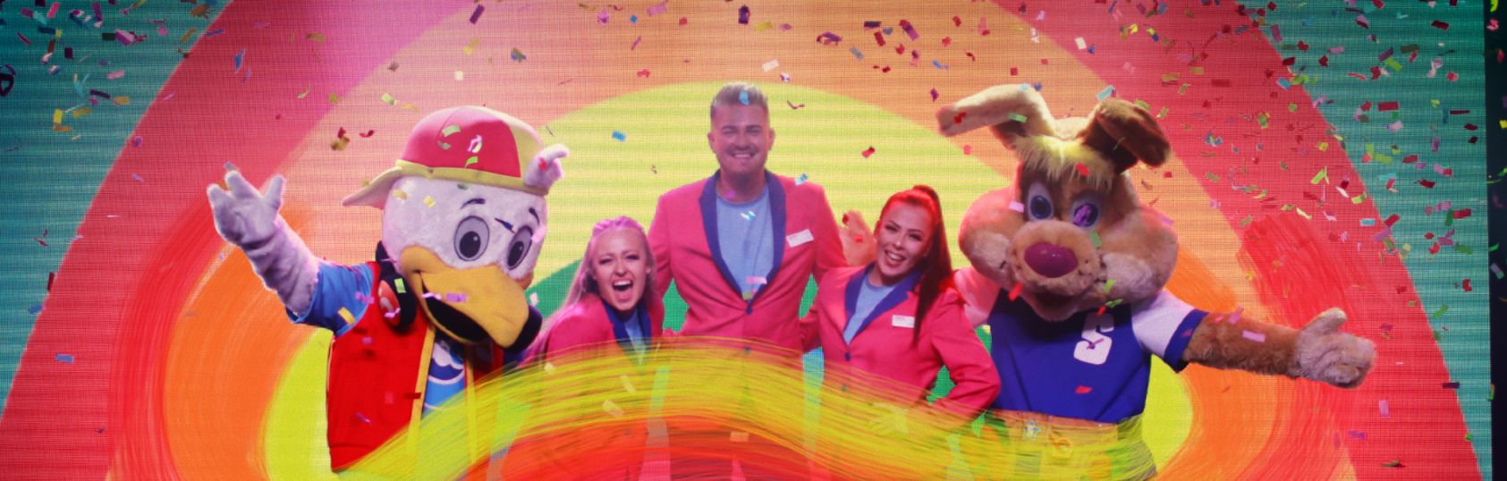 4 entertainers stand on stage with rainbow graphic