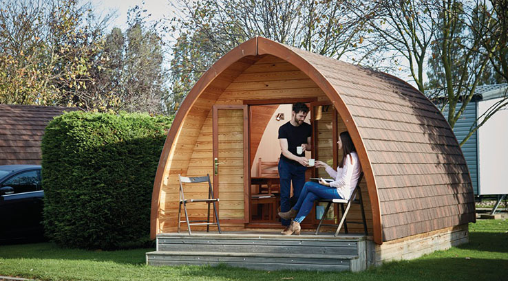 A couple relaxing outside their glamping pod at Vauxhall