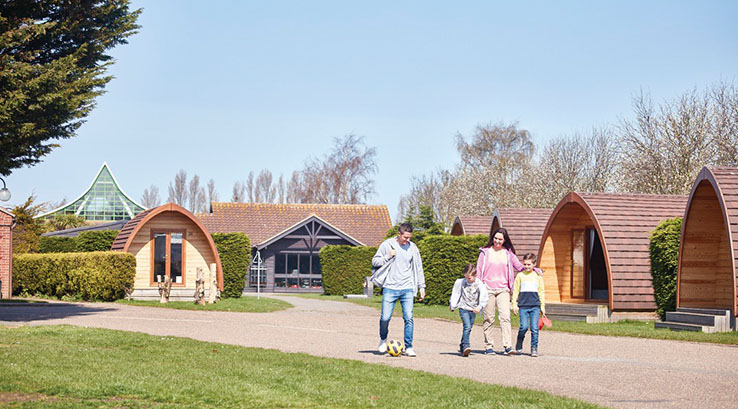A family walking through the village of glamping pods at Vauxhall Holiday Park