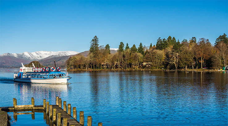 Windermere Lake in the Lake District with a boat sailing on it 