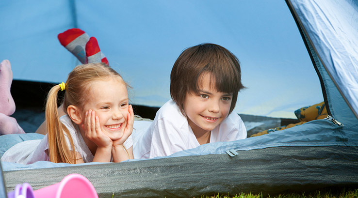 Two children inside a tent looking out