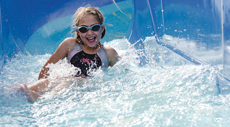A girl sliding down the flume at the outdoor swimming pool at California Cliffs Holiday Park