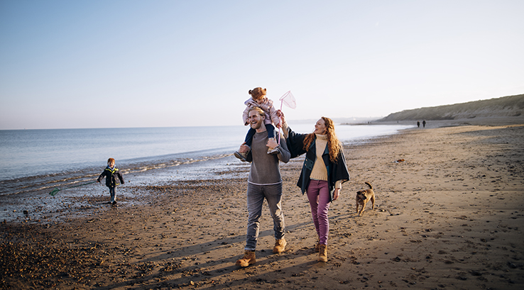 A family strolling along a beach in autumn sunlight