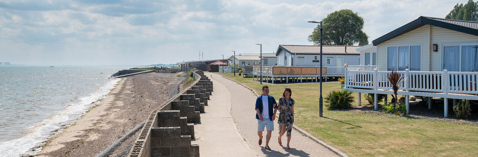 A couple walking along the seafront caravans at Coopers Beach Holiday Park