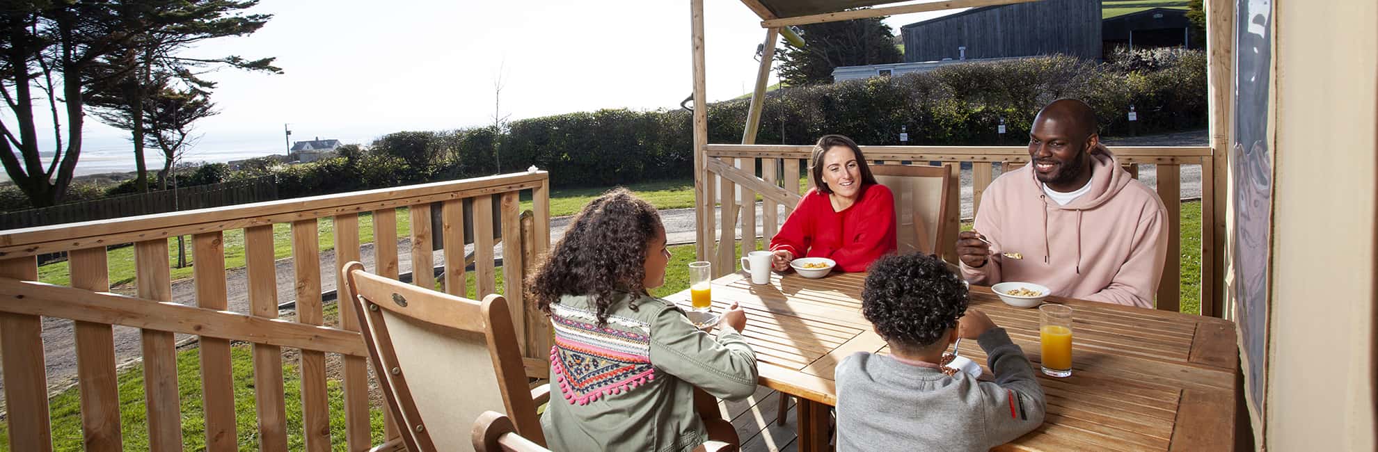 A family relaxing with drinks on the veranda of their glamping Safari Tent