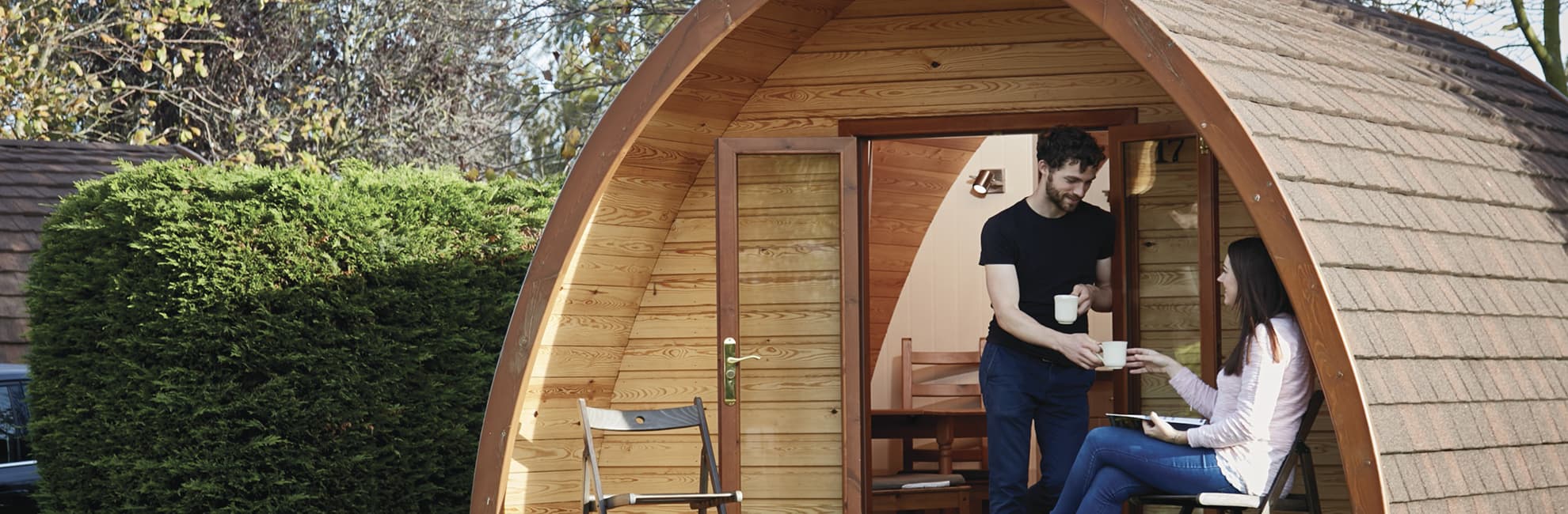 A couple relaxing outside their glamping pod at Ruda Holiday Park