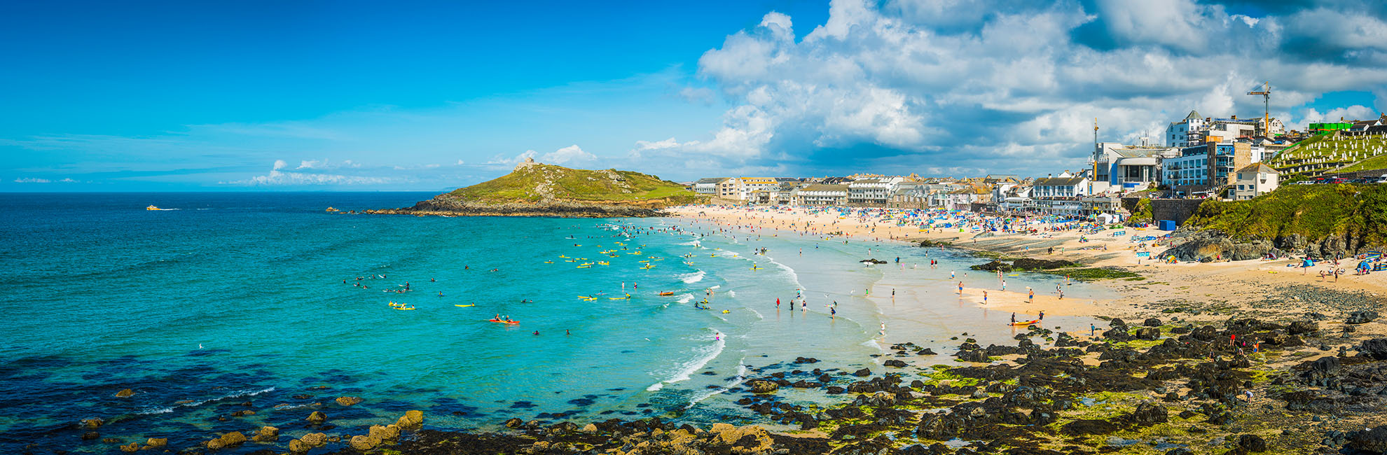 People swimming and relaxing on a sunny day at St Ives Beach in Cornwall
